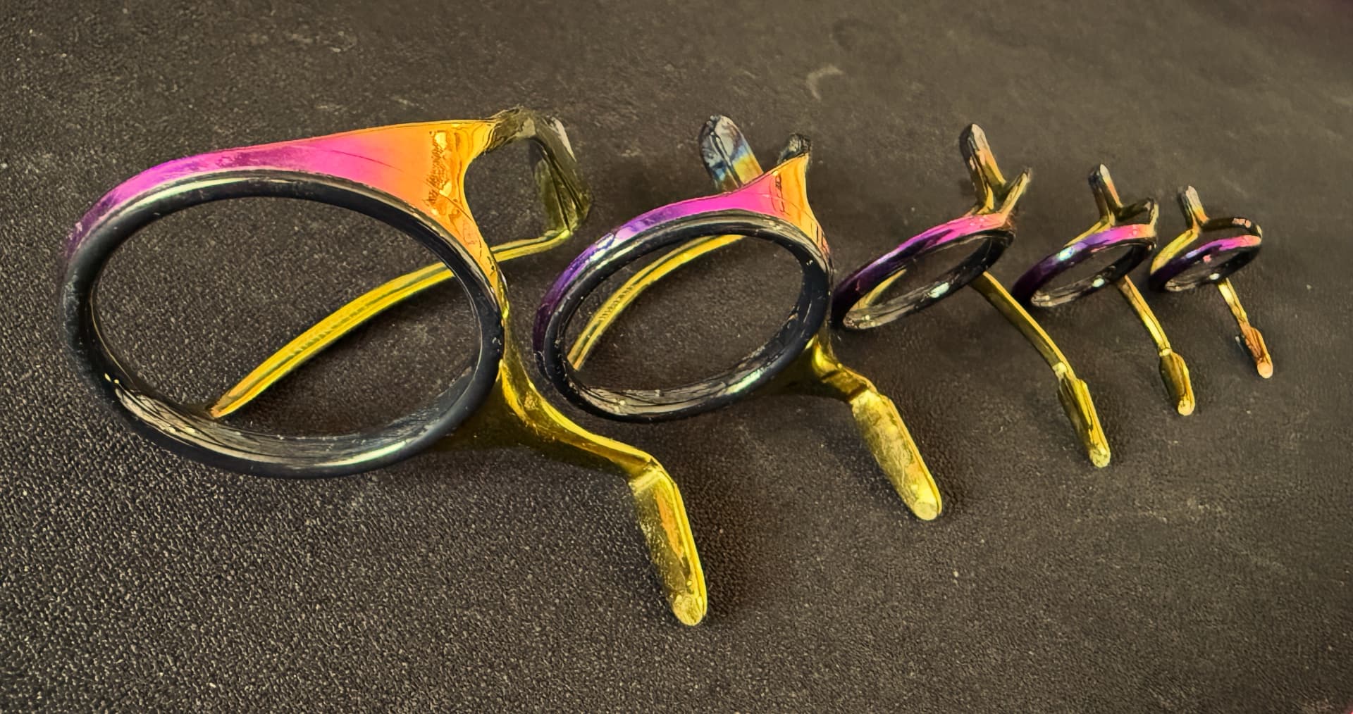 Set of rainbow titanium fishing rod guides arranged by size on the workshop bench